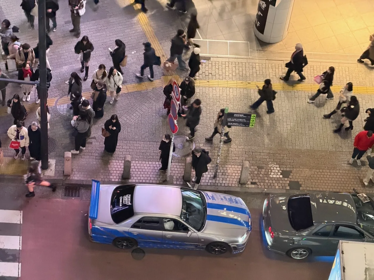 Sports cars and taxis waiting at Shibuya Crossing, seen from above